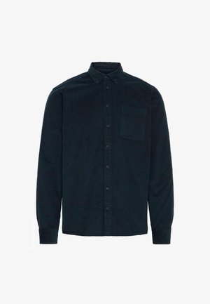 Temnozeleni korduroj srajc s dolgimi rokavi, z gumbi spredaj, ovratnikom v obliki pika in enim žepom na prsih. Teksture z navpičnimi rebri.