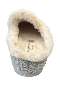Fluffy grijze slof met een zachte crèmekleurige voering en een gestructureerde buitenstof. Heeft een vlakke zool en een etiket dat zichtbaar is aan de binnenkant.