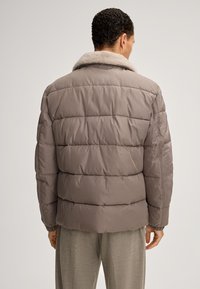 Grijze gewatteerde jas met een zachte beige kraag, voorzien van horizontale gestikte patronen en elastische manchetten, gezien vanuit de achterkant.