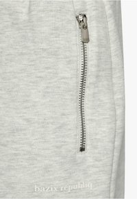 Light gray sweatpants with a smooth texture, featuring a metallic zipper pocket on the side and a logo at the bottom.