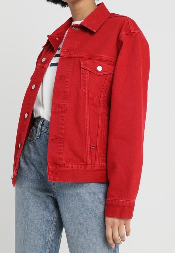 Veste en denim rouge avec un devant à boutons, un col pointu, deux poches poitrine et une coupe décontractée. Assortie à une chemise blanche rayée et à un jean bleu.