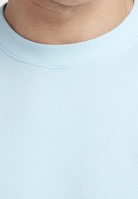 T-shirt azzurro chiaro in cotone a girocollo con texture liscia, colletto ribbed e design aderente, con dettagli di cucitura minimi.