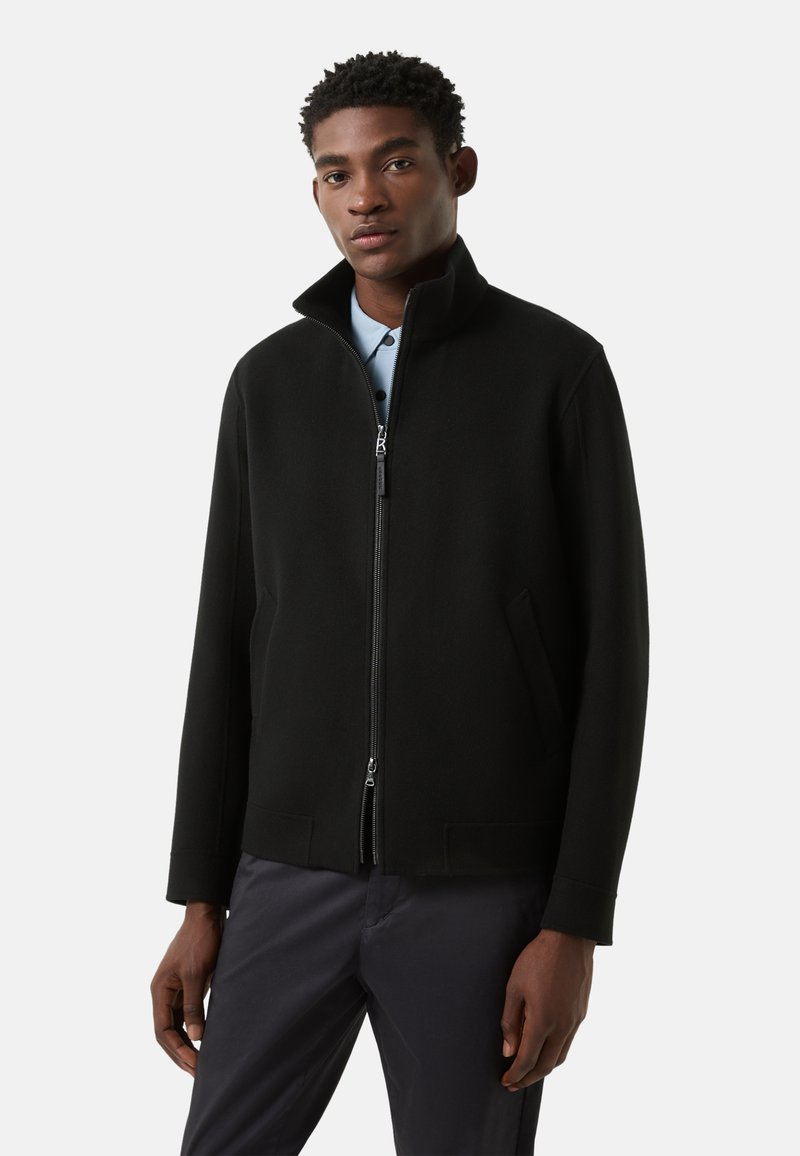 Sort lynlåsjakke med høj krave, sidelommer og ærmer i fuld længde; glat tekstur og minimalistisk design.