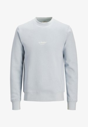 Svetlo modra majica s kratkim ovratnikom, dolgimi rokavi in majhnim belim logotipom "JJ Studios" na sredini prsnega koša.