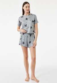 Kort grå pyjamas sæt med en kortærmet top og shorts med elastisk talje, pyntet med sorte sløjfer og prikker på et glat stof.
