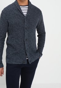 Dark blue knit cardigan with a shawl collar, featuring a textured pattern and two front buttons, worn over a striped shirt.