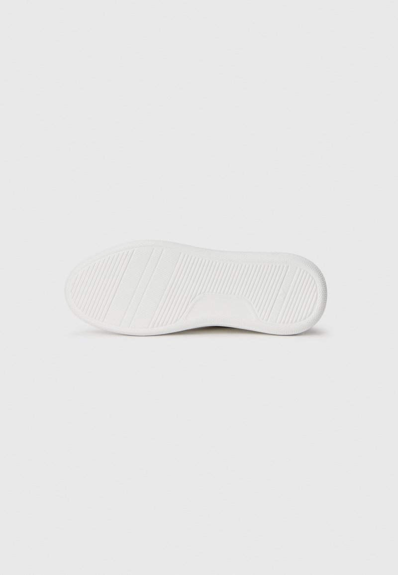 Sole di sneaker in gomma bianca con motivi a righe orizzontali e verticali, bordi lisci e una sezione del tallone leggermente rialzata.