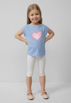 Lichtblauwe t-shirt met een roze hartgrafiek en tekst, gekleed met witte leggings en lichtroze schoenen. Glad, casual stof en pasvorm.