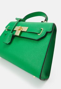 Green textured leather handbag with gold hardware, featuring a structured shape, top handle, and clasp closure. Black trim accents the design.