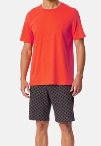 Heldere oranje T-shirt met korte mouwen, gecombineerd met zwarte shorts met een rood ruitpatroon. Katoenen stof met een gladde textuur.