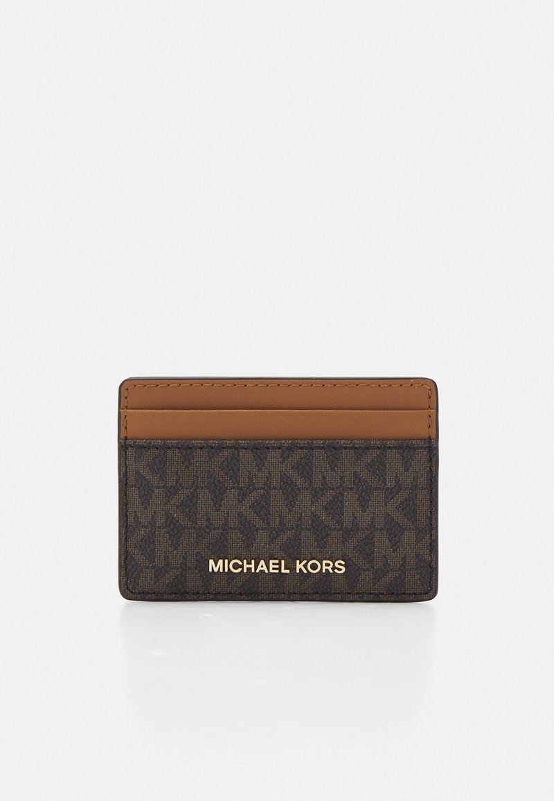 Michael Kors cardholder in brown with embossed logo pattern, featuring a tan accent stripe and gold logo text. Compact rectangular shape.
