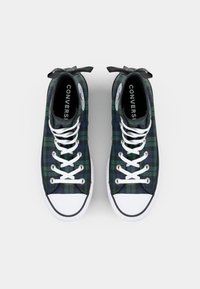 Höga sneakers med ett mörkgrönt och marinblått rutigt mönster, vita snören, gummitäckt tå och svartvit märkesinredning.