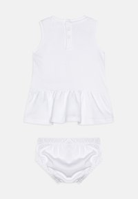 Biała bawełniana sukienka dla niemowląt z talią ozdobioną falbaną i dwoma guzikami z tyłu, w zestawie z pasującymi białymi bloomerkami.