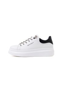 Sneaker bianco con suola a piattaforma spessa, dotato di accenti neri sul tallone e lacci argentati. Parte superiore realizzata in materiale sintetico liscio.