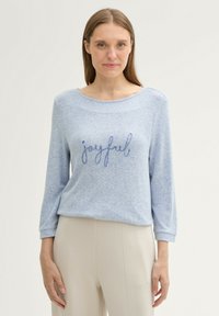 Világoskék, hosszú ujjú pulóver, laza szabással, sötétebb kék hímzett "örömteli" felirattal. Puha, texturált anyag.
