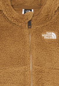 Rjava puhasta flis jakna z zadrgo in belim vezenim logotipom The North Face na prsih.