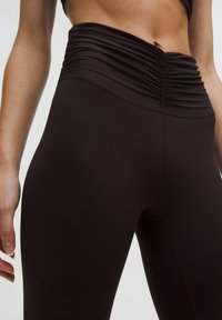 Leggings negre cu talie înaltă plisată, fabricate dintr-un material elastic, cu o textură netedă și cusături vizibile pe laterale.