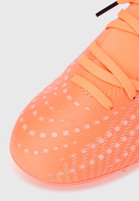 Πορτοκαλί αθλητικό παπούτσι με υφή στην επιφάνεια, διακοσμημένο με μοτίβο πλέγματος και ελαστικά κορδόνια. Στρογγυλεμένη μύτη με συνθετικό επάνω υλικό.