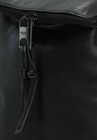 Borsa in pelle nera con una texture liscia, chiusura a zip e un sottile tassello in pelle attaccato alla zip. Branding sottile visibile.