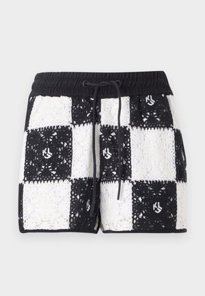 Pantaloni corti all'uncinetto in bianco e nero con motivo a scacchi, vita elasticizzata e chiusura con cordino. Presentano un logo sul tessuto.