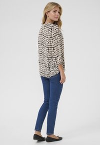 Kerge, mustriline beež ja must blouse 3/4 varrukatega, kombinatsioonis sobivate siniste teksade ja mustade balletikingadega.