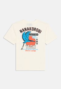 Kremna bombažna majica z modrim pticami in rdečim soncem. Besedilo pravi "Nanakorobi Yaoki Kyōto, Japonska" v izrazitih barvah.