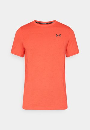 Svijetlo narančasta majica kratkih rukava od teksturirane tkanine, s crnim logotipom Under Armour na lijevoj strani prsa i okruglim izrezom na vratu.