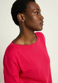 Fuchsia sweater featuring a crew neckline and relaxed fit, made from soft knit material, with a smooth texture and minimal design details.