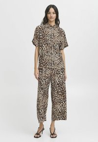 Ensemble assorti à imprimé animal comprenant une chemise à boutons à manches courtes et un pantalon large dans des tons beiges et bruns, fabriqué en tissu léger.