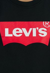 Fekete pamut póló, nagy vörös Levi's logóval, fehér szöveggel és íves grafikával az alján. Klasszikus kerek nyakú dizájn.
