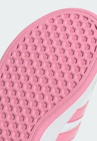 Sola di scarpa da ginnastica rosa con un motivo esagonale testurizzato, dettagli laterali bianchi e strisce orizzontali rosa strette.