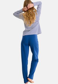 Gestreepte langemouwen top in marineblauw en wit, gecombineerd met effen blauwe broek. De outfit heeft een ontspannen pasvorm en zachte stof.