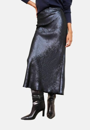 Must mähkme seelik mustast satiinist, sujuva ja läikiva tekstuuriga, väikese ebaühtlase allääraga, kantud teravapealsete mustade kontsaga kingadega.