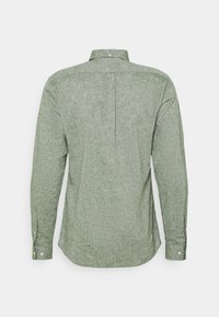 Košile s dlouhými rukávy, světle zelená, texturovaná tkanina, límec na knoflíky, zadní prošití a detail postranního záhybu, s knoflíkovými manžetami a zaobleným lemem.