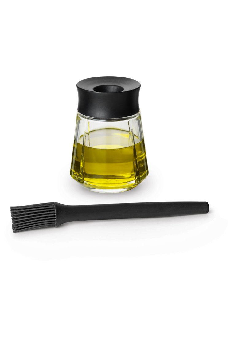 Glasbehälter mit einem schwarzen Deckel, gefüllt mit gelbem Öl, begleitet von einem schwarzen Silikonpinsel mit einem gerippten Kopf.