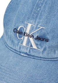 Căciulă de baseball din denim albastru, cu broderie albă "CK" și logo-ul "Calvin Klein Jeans". Formă structurată cu un vizor curbat.