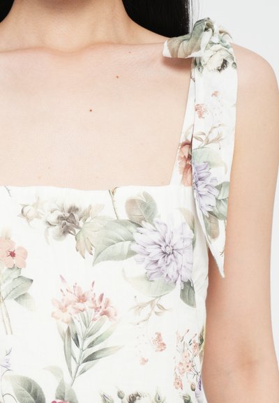 Floral dress featuring a white background with pastel pink, purple, and green flowers. Bow tie straps and square neckline design.