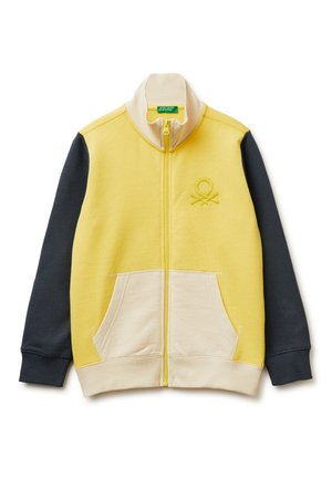 Gele jas met rits, crèmekleurige kraag en zakken, donkergrijze mouwen en een klein reliëflogo op de linkerborst.