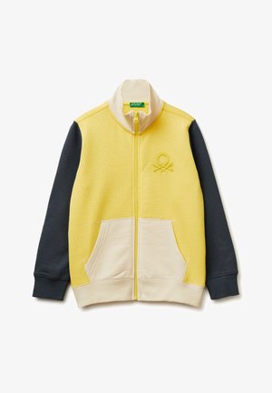 Giacca gialla con zip, colletto e tasche crema, maniche grigio scuro e un piccolo logo in rilievo sul petto sinistro.