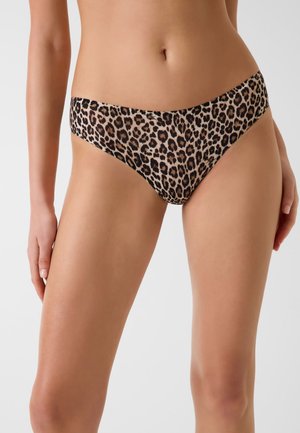 Kobieta w bieliźnie bikini w panterkę, pokazana od talii do górnej części ud na jednolitym tle.