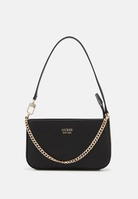 Mustavahainen käsilaukku, jossa on teksturoitu pinta, kullanvärinen ketju, irrotettava olkahihna ja etupuolella "GUESS EST 1981" -logo.