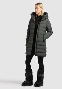 Tumeheline puffer-mantel kapuutsiga, vertikaalse tikandiga, ees lukuga ja küljetaskutega. Sobitatud mustade isoleeritud lumesaabastega.