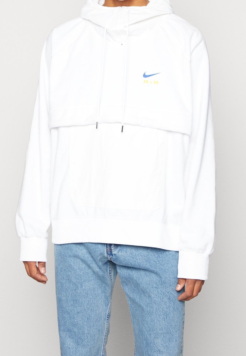 Valkoinen huppari, jossa on korkea kaula-aukko, säädettävät nyörit ja etutasku. Sisältää sinisen ja keltaisen Nike AIR -logon. Pehmeä kangasrunko.
