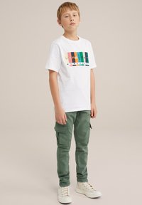 Bela bombažna majica s pisanimi grafičnimi elementi iz Minecrafta. V kombinaciji z zelenimi cargo hlačami in belimi supergami. Slim fit, sproščen dizajn.