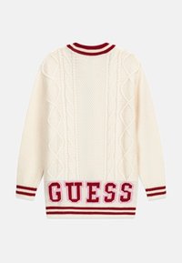 Pull en maille torsadée crème avec un col côtelé rayé rouge et blanc, des rayures rouges sur les manches, et un logo "GUESS" bien en vue à l'ourlet.