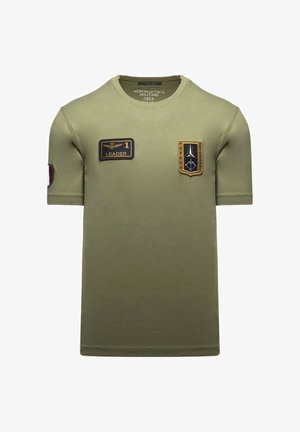 T-shirt verde oliva a maniche corte con due toppe in stile militare sul petto e logo Aeronautica Militare all'interno del colletto.