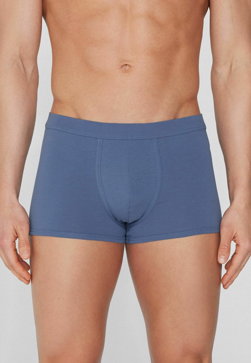 Męskie niebieskie bokserki, wykonane z miękkiej, elastycznej tkaniny; zawierają wsparcie w przedniej części oraz gładką gumkę w talii. Dopasowany krój.