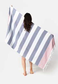 Striped beach towel made of cotton, featuring gray, white, and red stripes with fringed edges. Lightweight and large, held by a person.