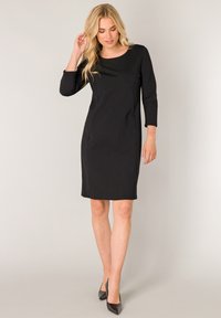 Zwarte jurk tot op de knie, gemaakt van een gladde stof, met een ronde halslijn en driekwart mouwen, een aansluitende pasvorm en zijzakken.