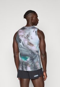 Ärmelloses Sportshirt mit einem mehrfarbigen, abstrakten Design in Grautönen, Blau und Pink. Verfügt über eine strukturierte Oberfläche und ein dezentes Logo.